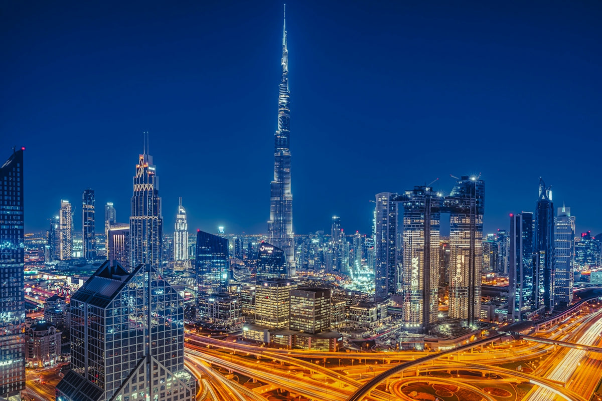 The Burj Khalifa towering over the illuminated Dubai skyline at night with busy highways