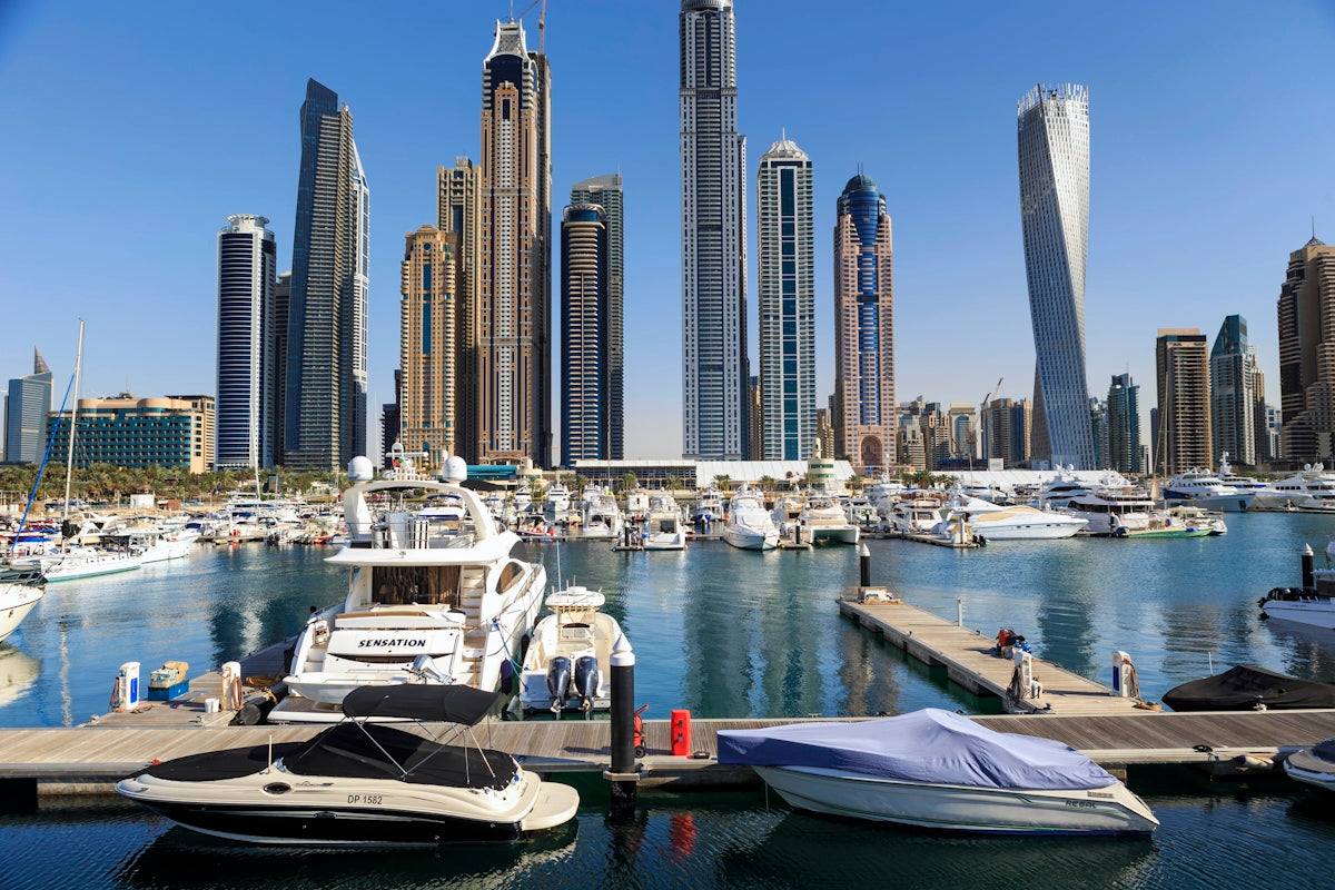 Boats and skyscrapers line a beautiful harbor.